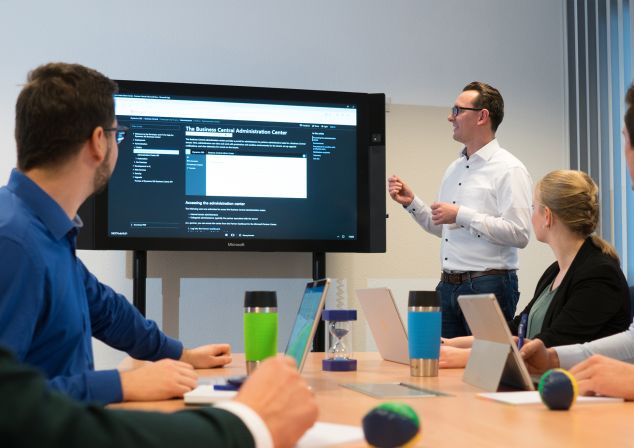 Softwareentwickler beraten gemeinsam im Büro von AKQUINET. Ein Softwareentwickler präsentiert seine Ergebnisse auf einem Bildschirm.