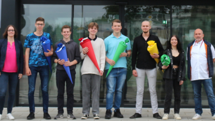 Unser sechs neuen Kolleg*innen für die Ausbildung als Fachinformatiker*in für Systemintegration stehen mit Personalreferentin Sonja und Ausbildungsleiter Andreas vor der Tür.