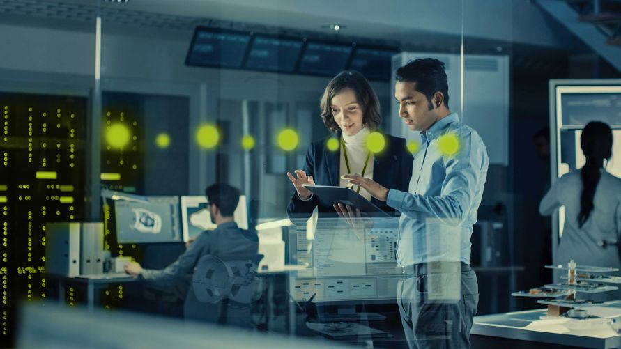 Eine Frau und ein Mann arbeiten im Stehen gemeinsam an einem Tablet Computer