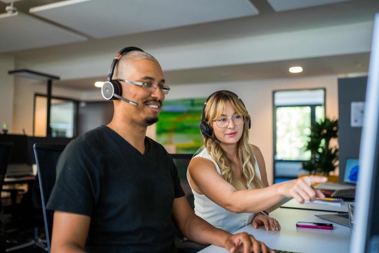 Zwei Mitarbeitende sitzen an einem Arbeitsplatz vor einem Bildschirm