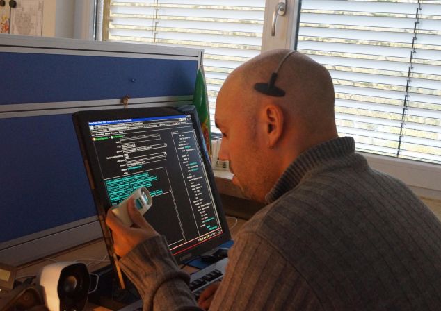 Ein Mitarbeiter der AKQUINET arbeitet aufgrund seiner Sehbehinderung mit Hilfe einer Bildschirmlupe an einem digitalen Arbeitsplatz.